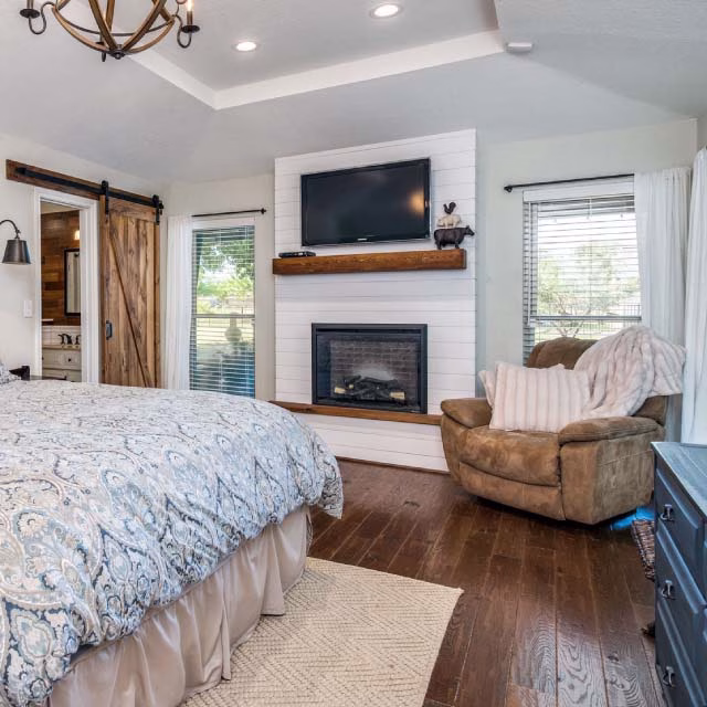Cozy bedroom featuring a warm fireplace and a neatly made bed, creating a welcoming and relaxing atmosphere.